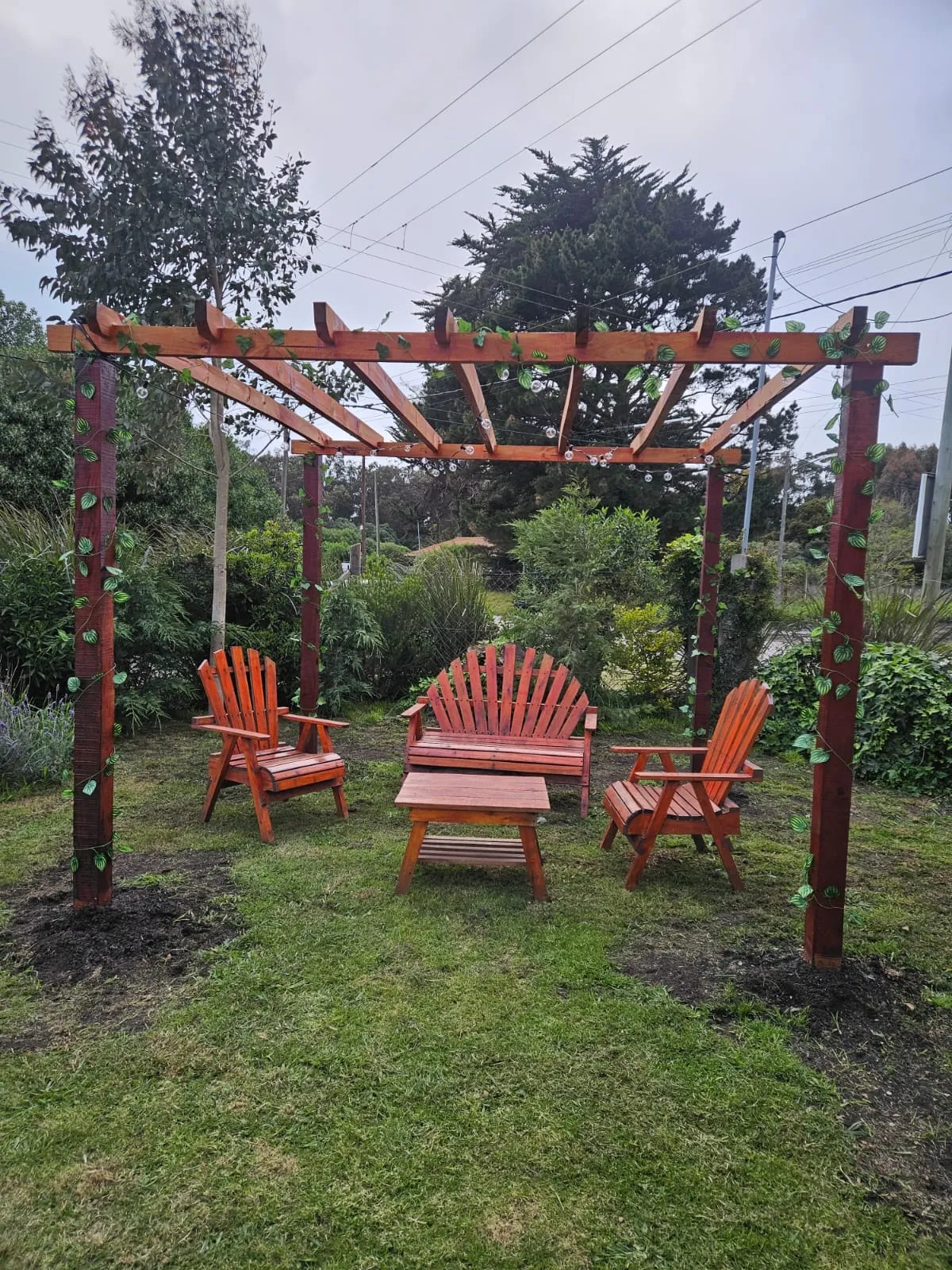 Pérgola de madera con sillones naranjas en el parque